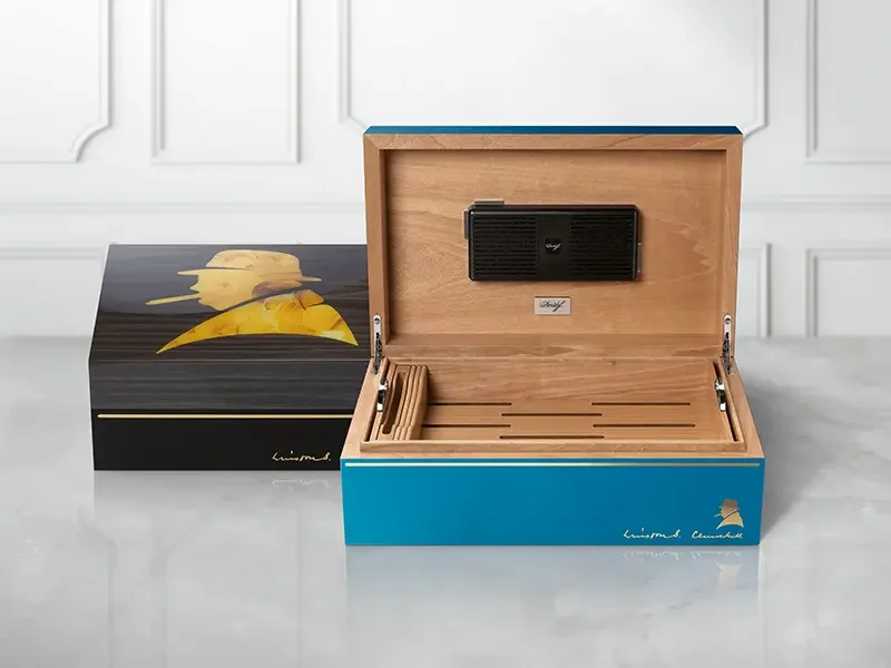 Ein dunkelgrauer Davidoff Winston Churchill Humidor in Primos-Grösse neben einem geöffneten Ambassador Humidor.