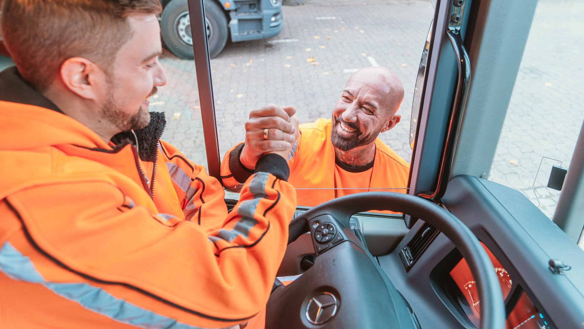Foto von zwei Mitarbeitern der Berlin Recycling, die sich die Hand reichen