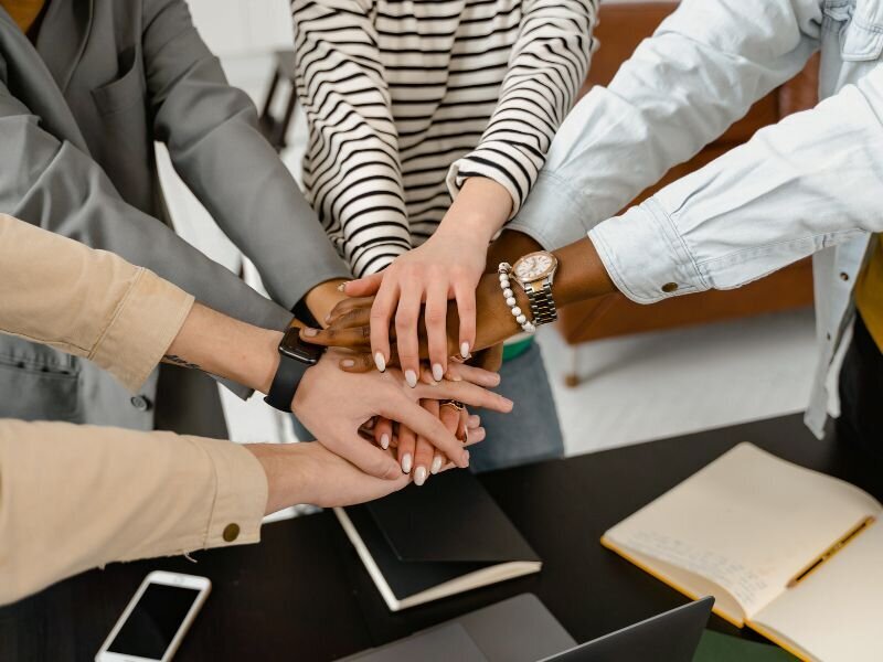 Diverse group of employees stacking hands in a show of workplace teamwork