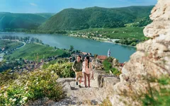 A couple hiking up a mountain nearby a castle in Durnstein, Austria