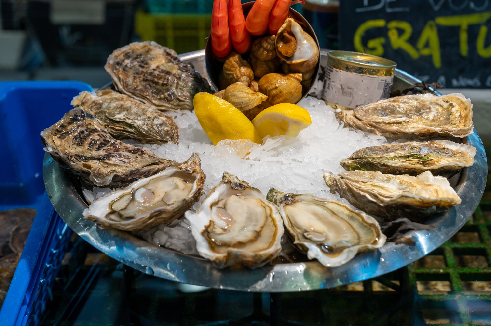 Plate with fresh live oysters with citron on ice in market hall to eat for lunch from oyster-farming village, Arcachon bay, Gujan-Mestras, Bordeaux, France