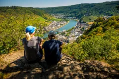 Two people sitting at the top of a hill or mountain after hiking to the top