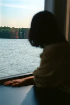 Woman looking out of ship window at river