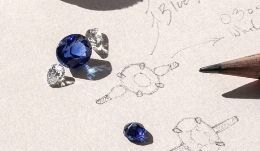 Blue sapphire and diamonds beside hand-drawn ring design