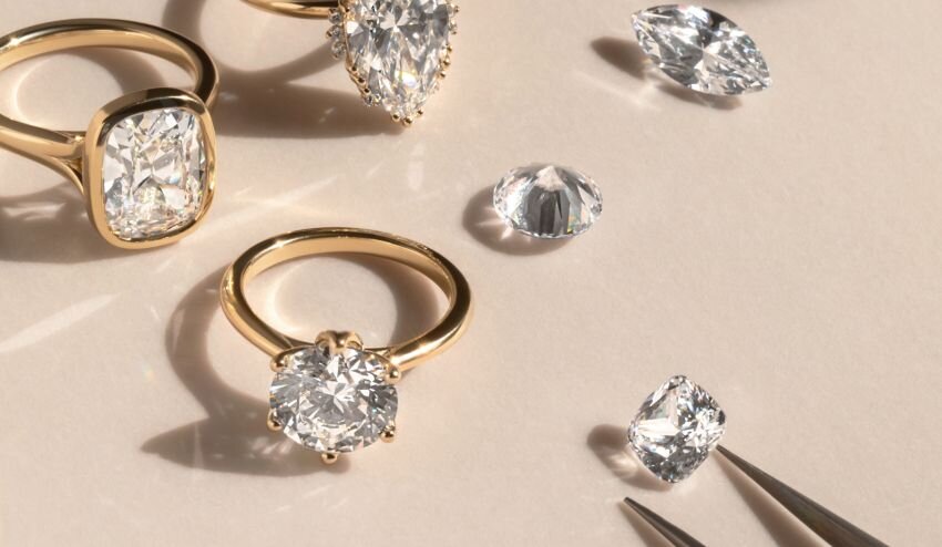 Gold diamond engagement rings with loose diamonds and jeweller tweezers