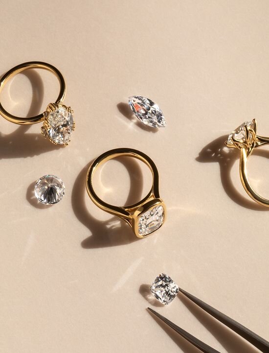 Gold engagement rings with loose diamonds and jeweller tweezers
