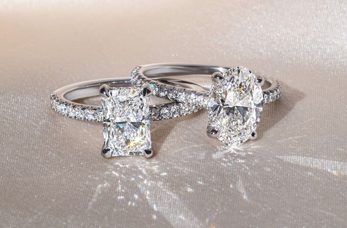 Radiant and oval diamond engagement rings on satin fabric