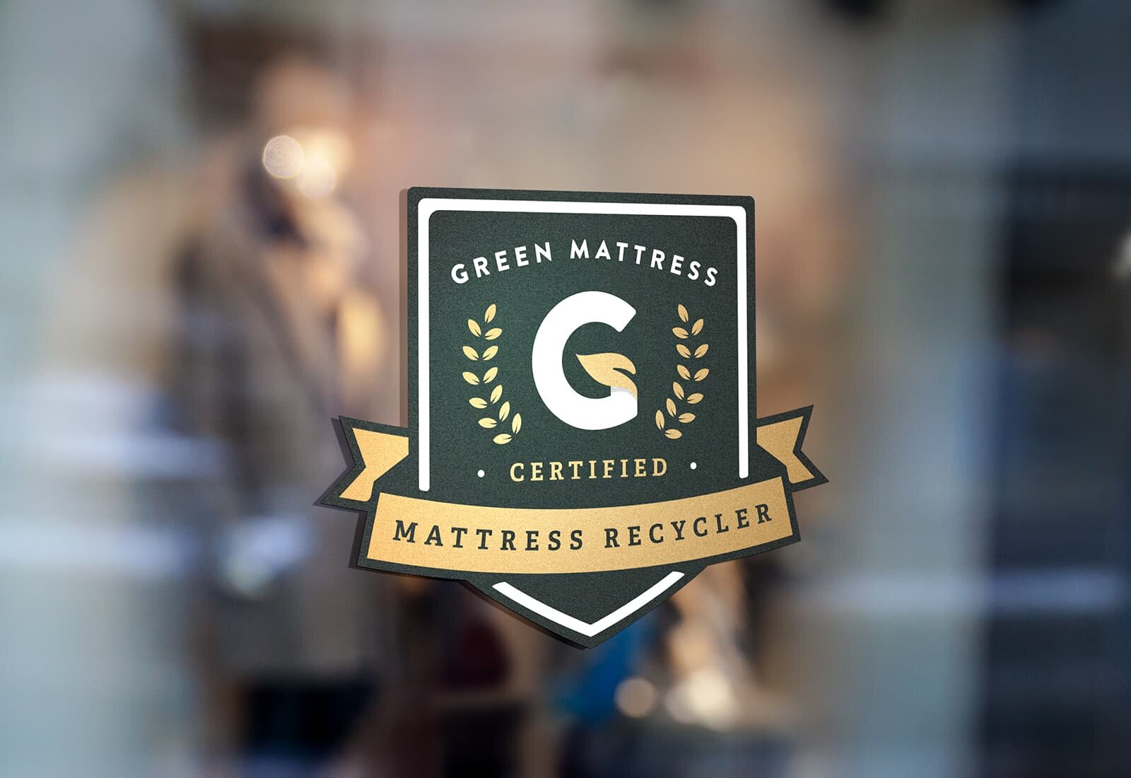 The Green Mattress certification badge on a shiny window