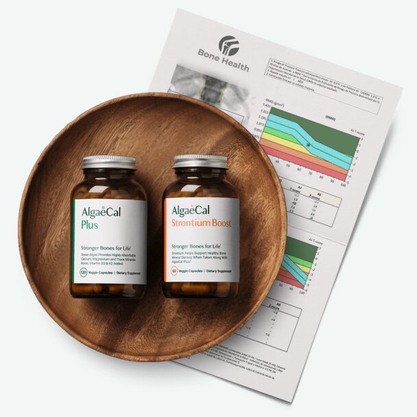  A round, dark wood bowl holds two brown bottles of AlgaeCal supplements: "AlgaeCal Plus" and "AlgaeCal Strontium Boost." Next to the bowl is a partially visible bone density scan (DEXA scan) report, with charts and numbers.