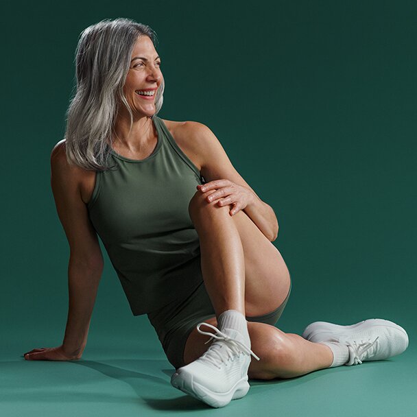 Woman with long grey hair sitting with her one knee up