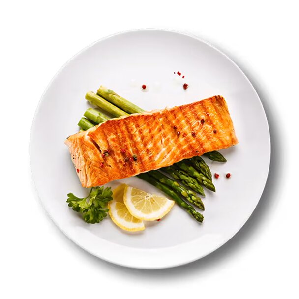 An overhead view of a plate of  salmon on a bed of asparagus , with lemon slices on the side.