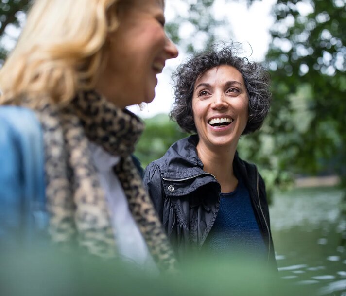 Two women walking and laughing with forested background