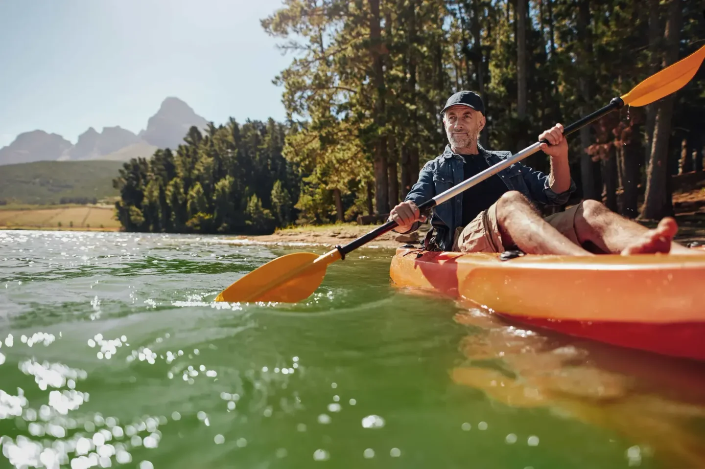 Man kayaking with low mountains in the background
