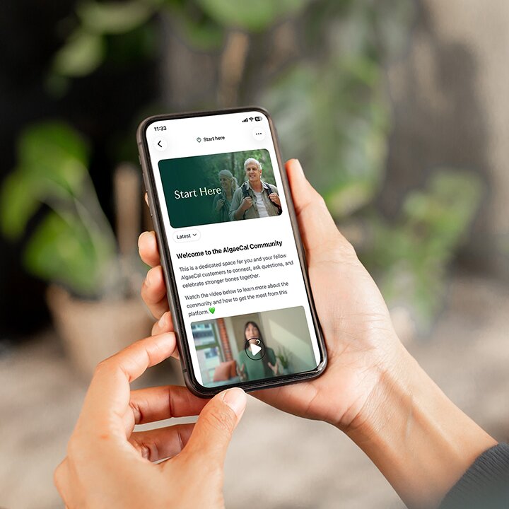 Hands holding a cell phone with the AlgaeCal Community app open