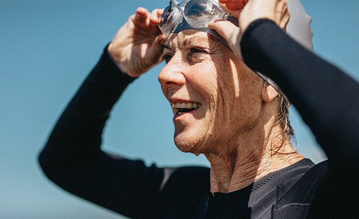 Close-up of woman's face with her hands lifting swimming goggles onto her head