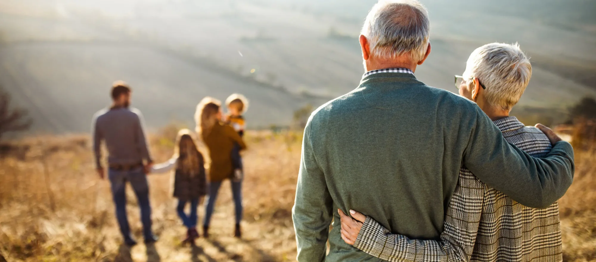 An older couple watching their family walk ahead of them