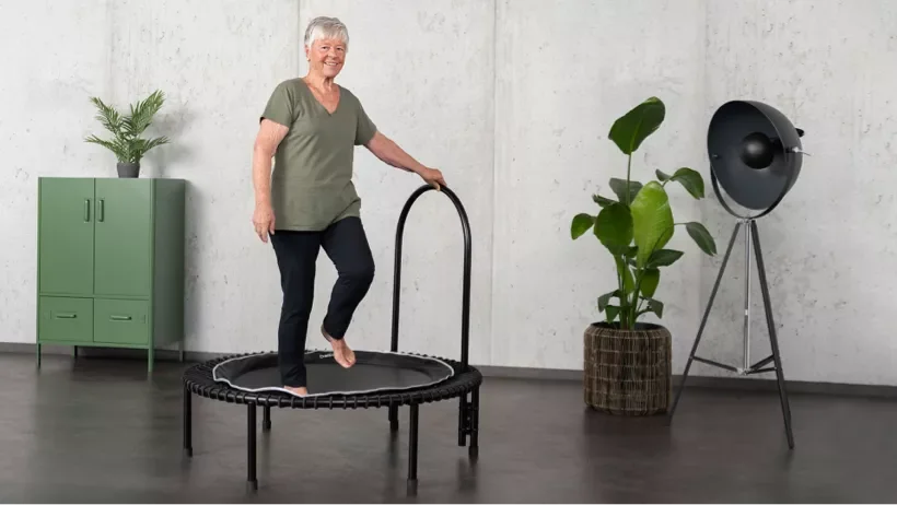 An elderly woman is working out on the bellicon health rebounder.