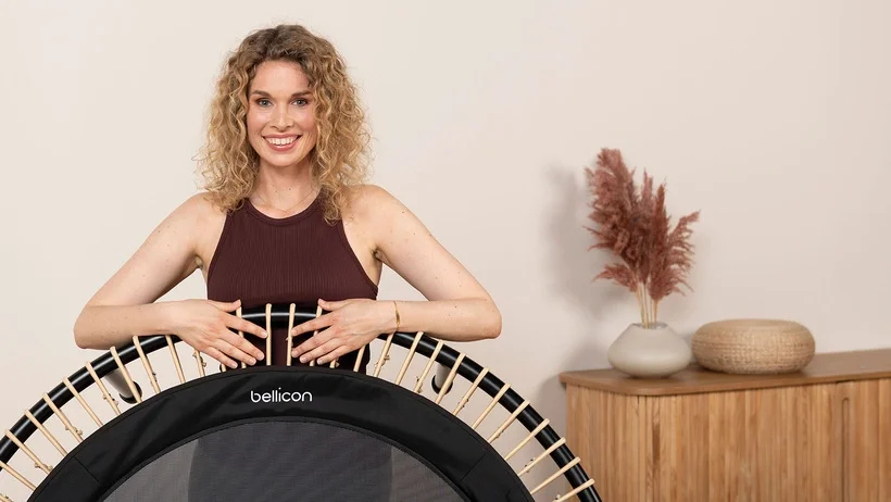Une femme sourit, s’appuie sur le bellicon et se réjouit de son entraînement.