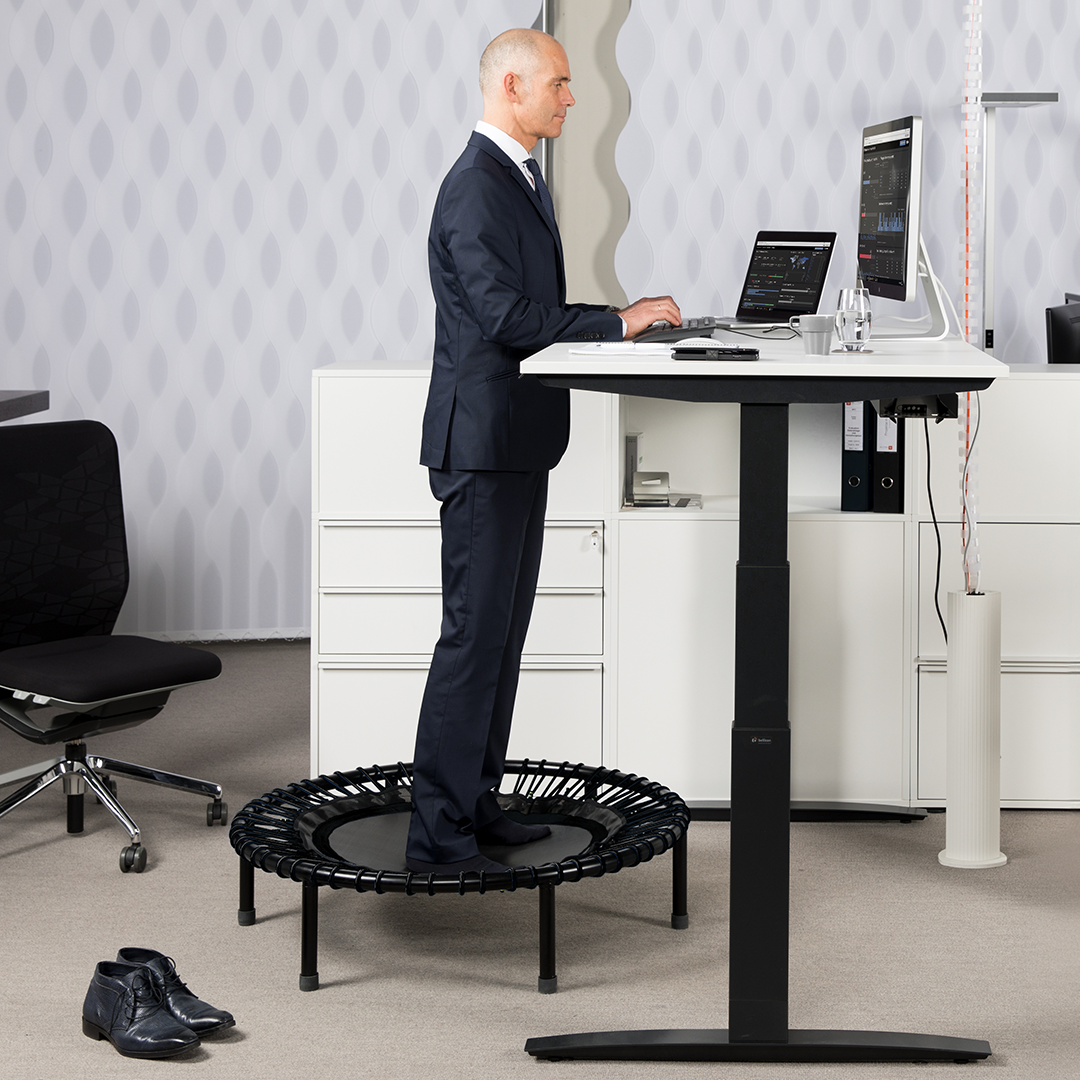 Man stand on the bellicon rebounder on a desk for soft exercise.