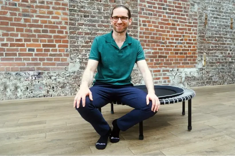 Axel Heil is sitting on the bellicon mini-trampoline.