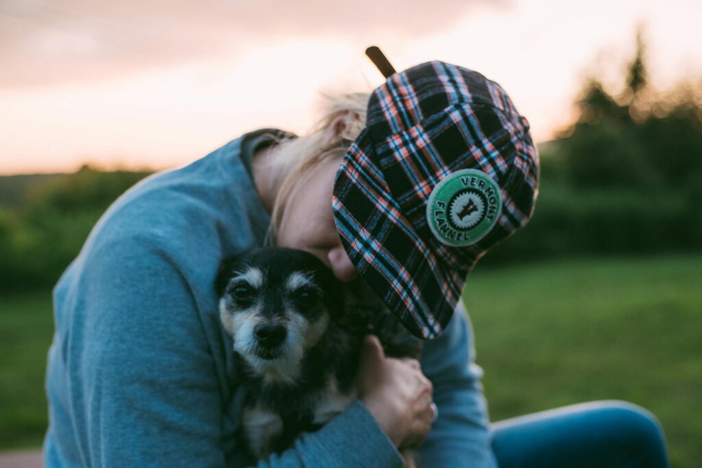 woman earing cap cuddling dog