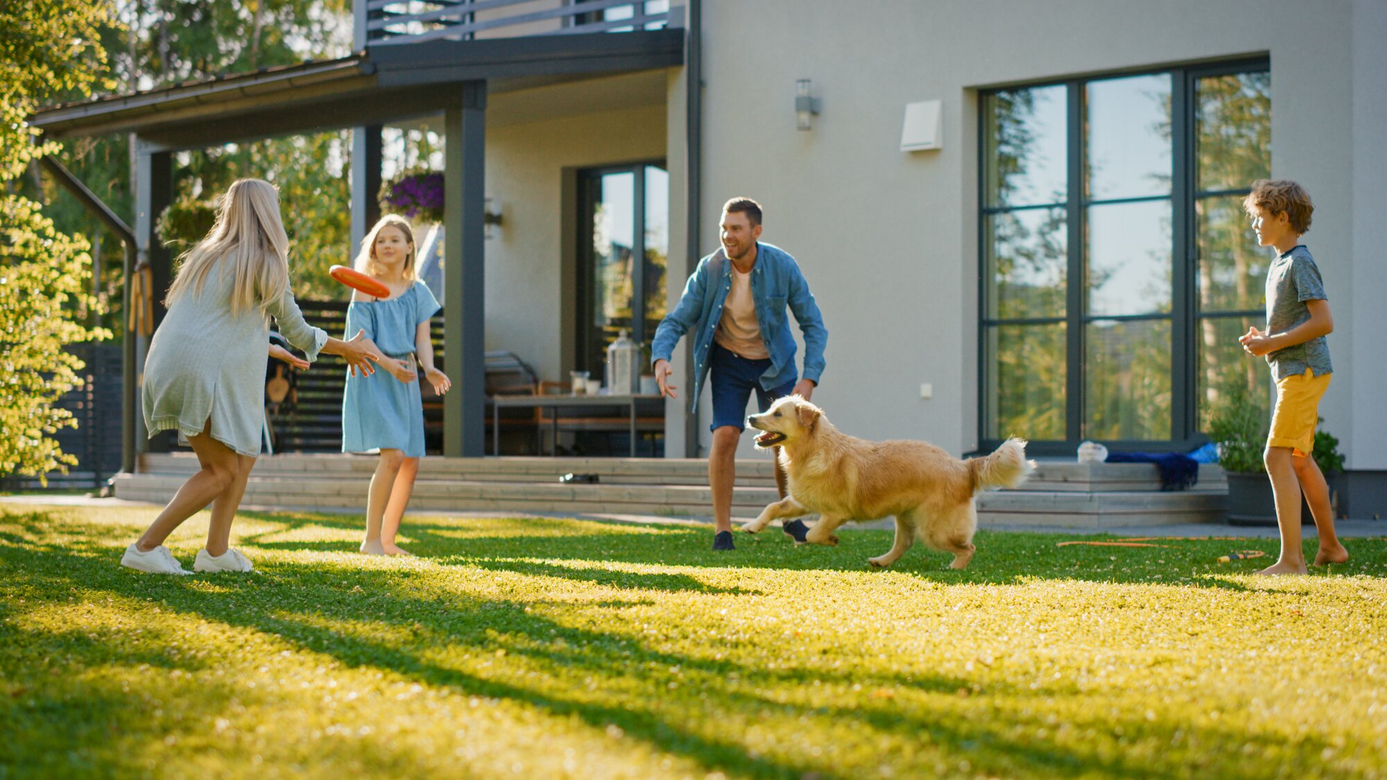 family in backyard playing frisbee with their dog 