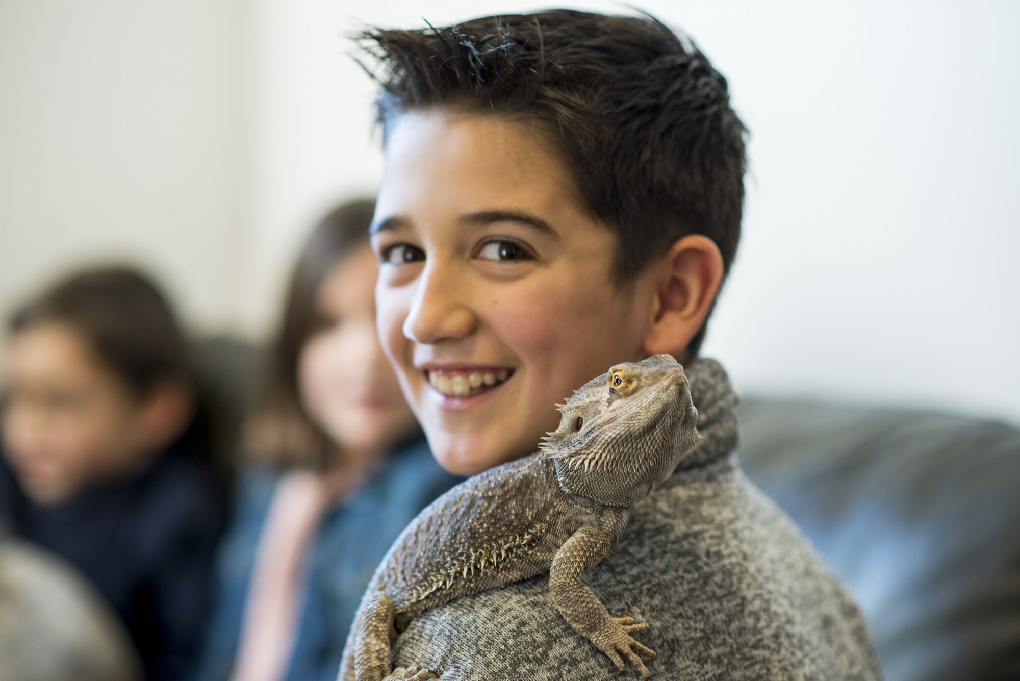 boy smiling at camera with a bearded lizard on his shoulder