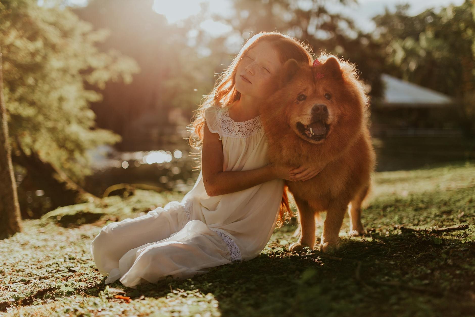 girl sitting on grass cuddling her chow chow dog 