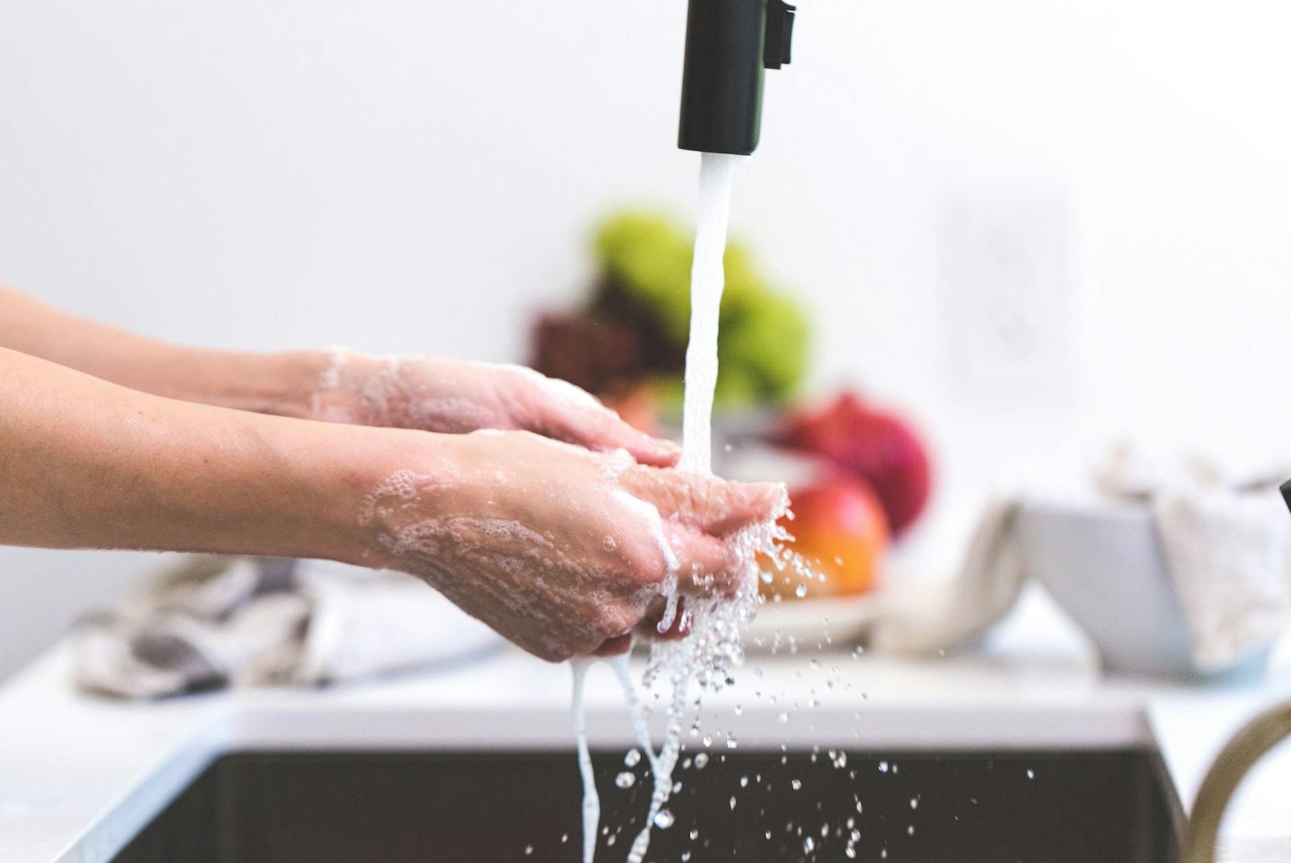 person washing hands under tap in kitchen