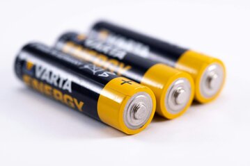 3 AA batteries lying on a white bench