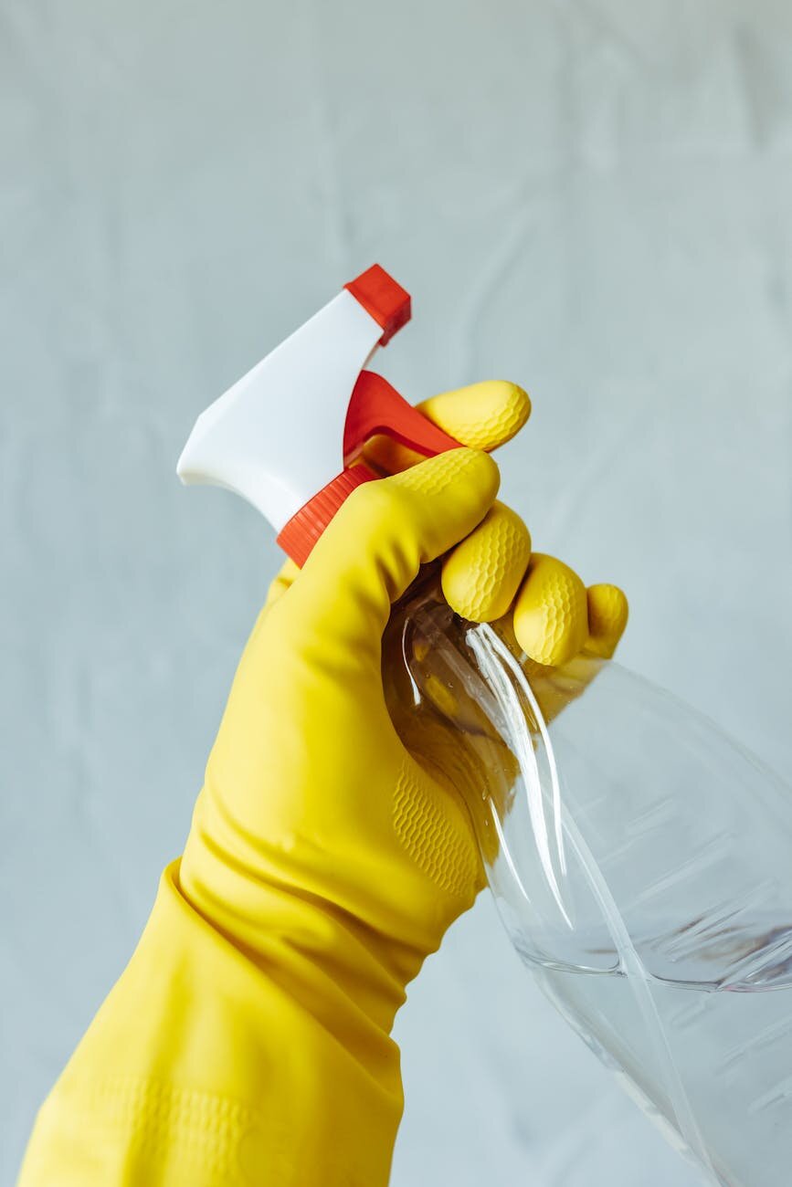 a gloved hand holding a spray bottle