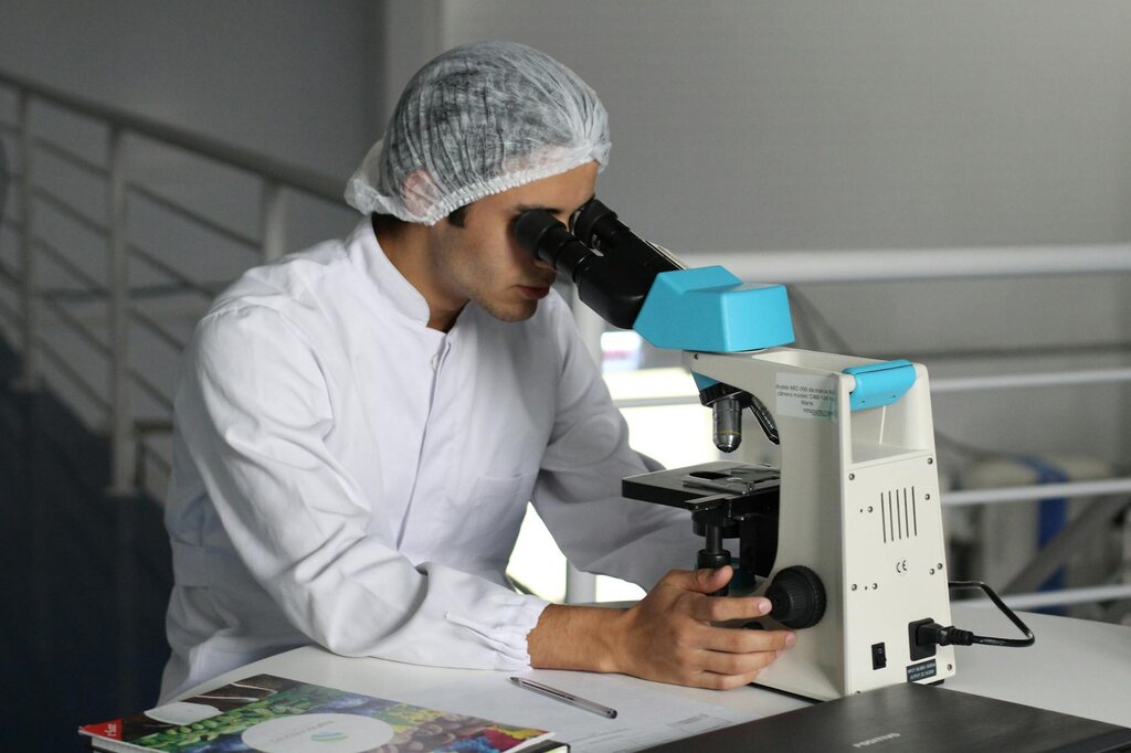 scientist looking down microscope