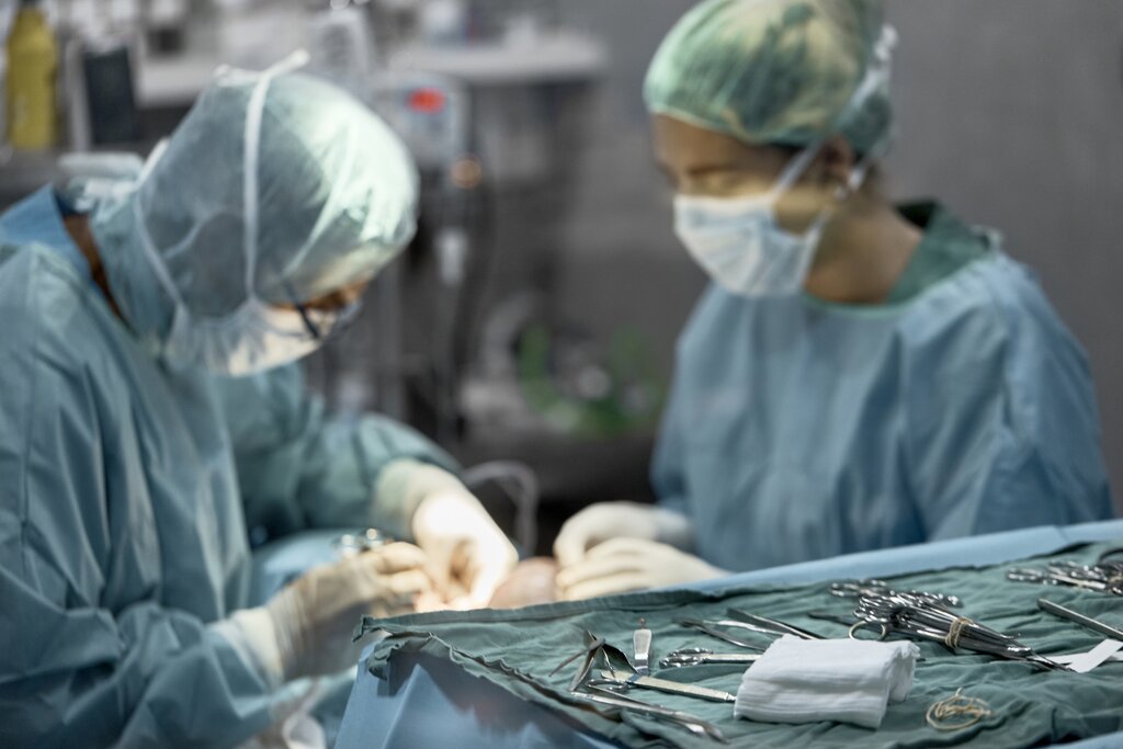 close up of surgical instruments with 2 vets doing surgery in the background