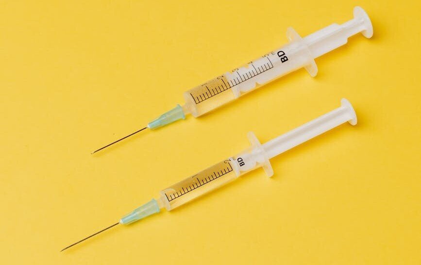 two syringes on yellow background