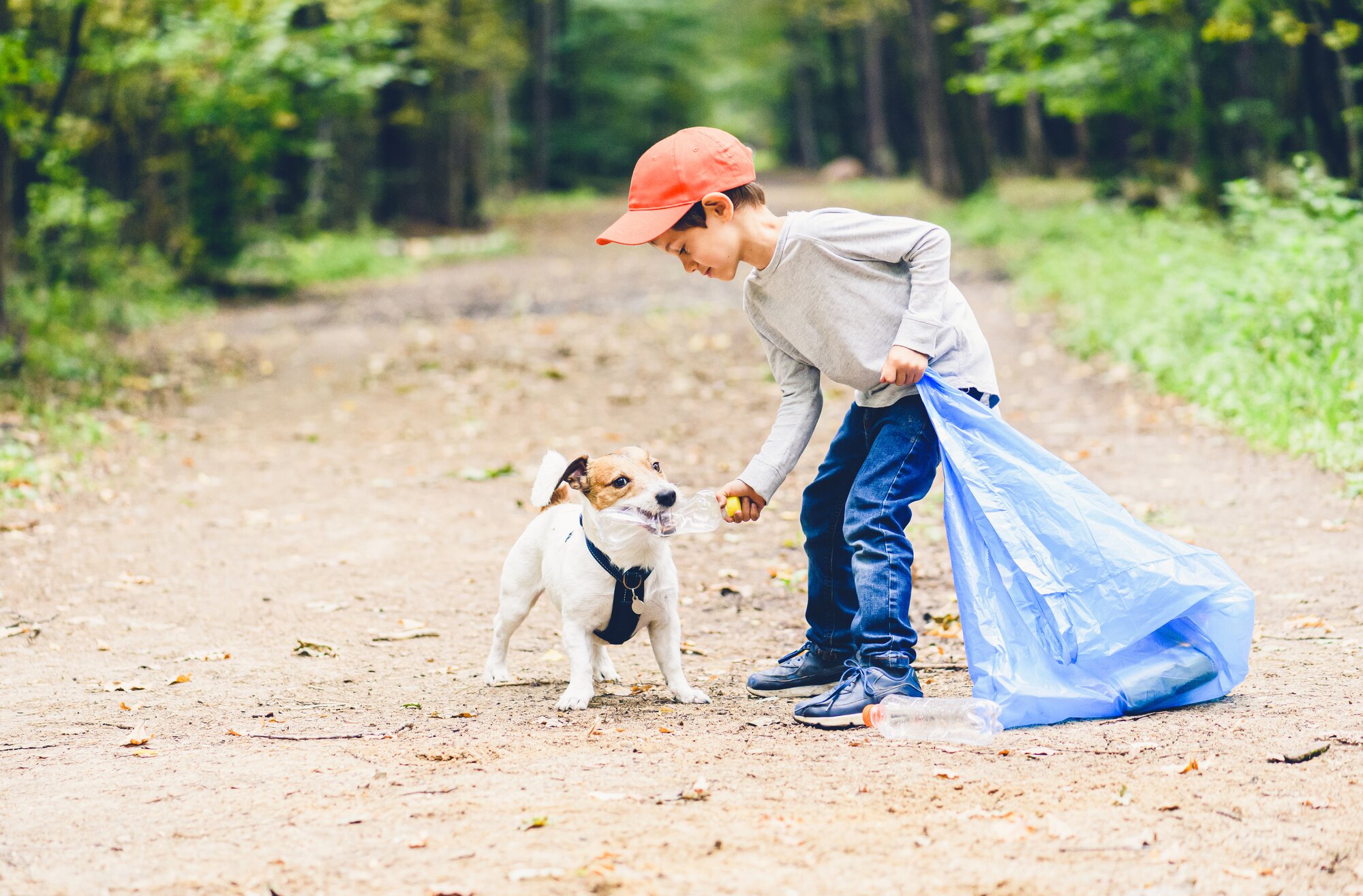 boy picking up rubbish with his pet dog