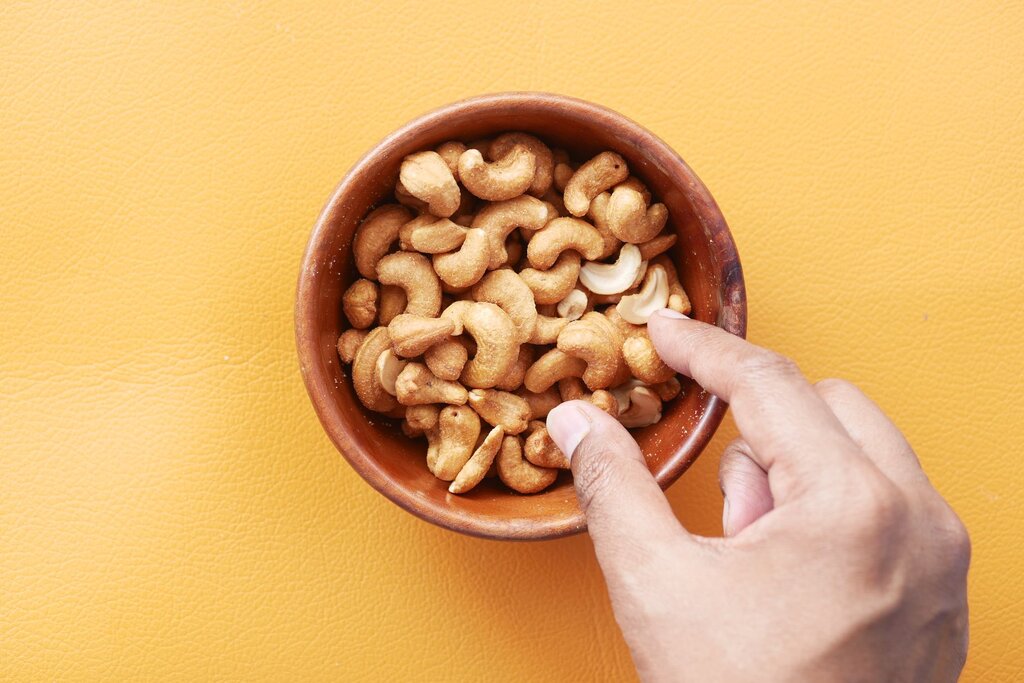 hand reaching into a bowl of cashews
