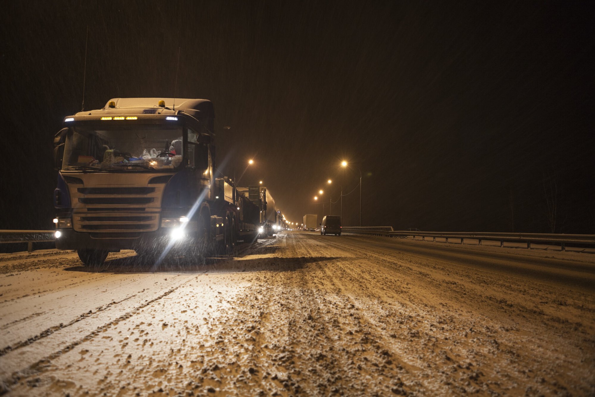 Long traffic jam is on wintry federal road M10 at evening time. Semitrailers standing to Moscow direction due road accident. Snowfall. Russia. Adobe Stock image.