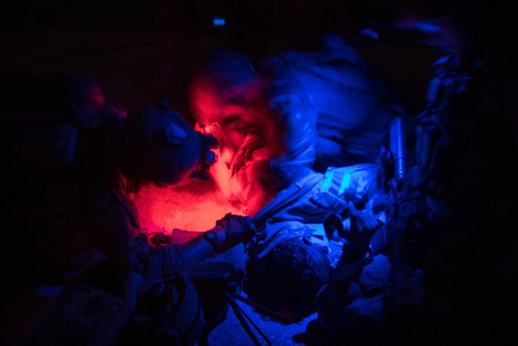 U.S. Air Force Special Tactics operators roll a patient to check for simulated bullet exit wounds during operability training at Eglin Range, Florida, April 22, 2020. Photo by Staff Sgt. Rose Gudex/U.S. Air Force. coffee or die