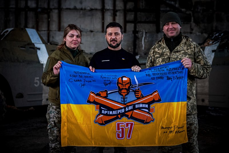 Ukrainian president Volodymyr Zelenskyy, center, and Ukrainian soldiers hold the flag of a military unit at a position near Bakhmut, Donetsk region, Ukraine, Wednesday, March 22, 2023. Ukrainian Presidential Press Office via AP.