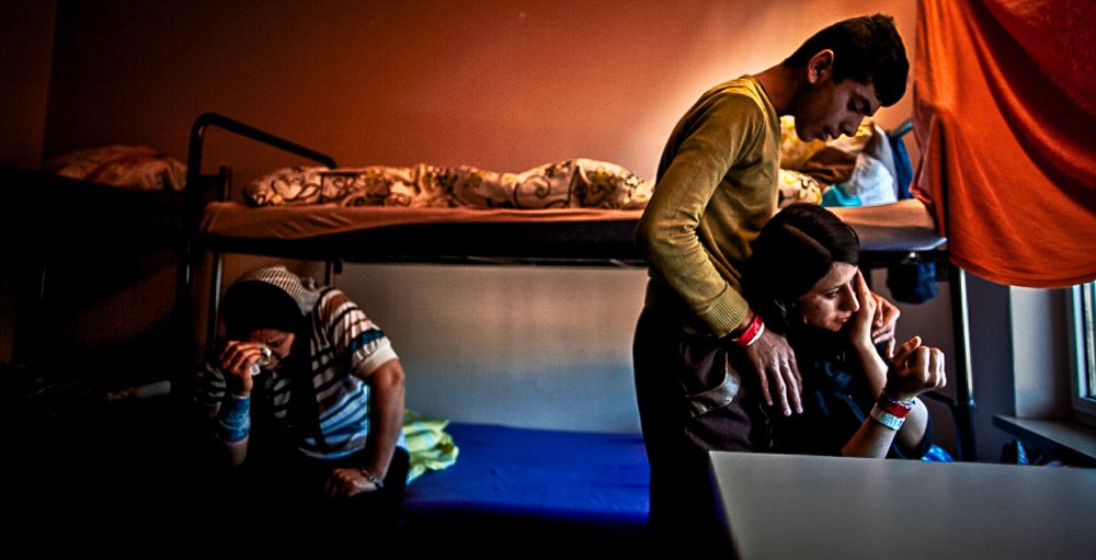 A refugee from Iraq is comforted by her brother.