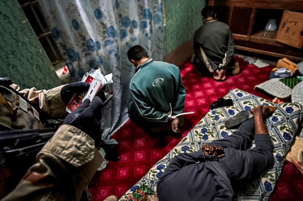 An Iraqi interpreter working for the U.S. Army inspects identity papers for men detained during a raid by soldiers from the 101st Airborne Division in Ramadi.