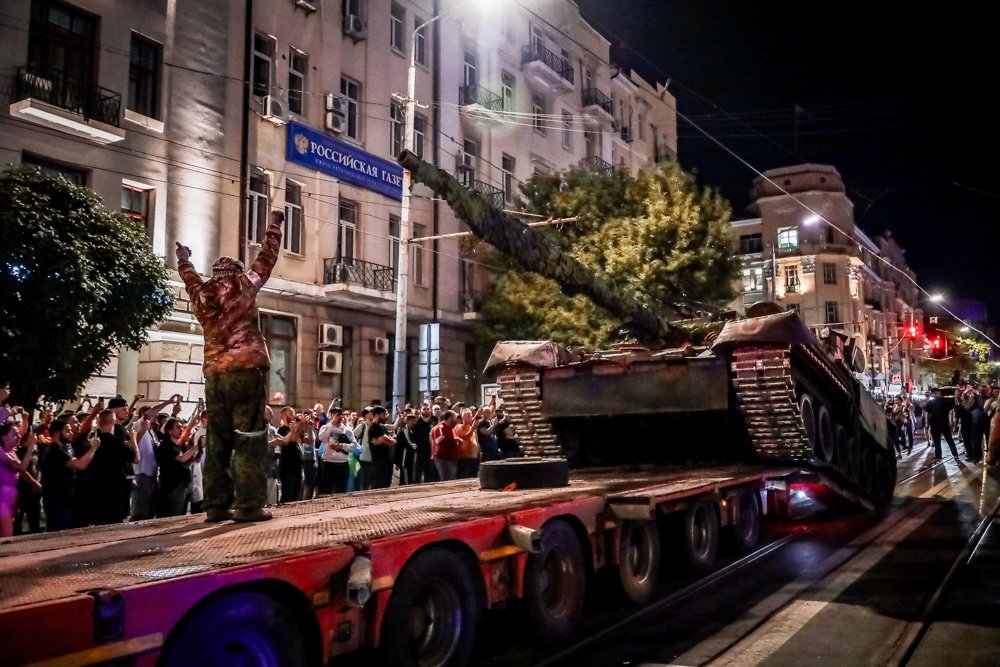 Members of the Wagner Group military company load their tank onto a truck on a street in Rostov-on-Don.