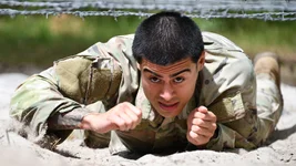 A soldier low crawls under barbed wire June 28, 2022, at the 7th Army Training Command's Grafenwoehr obstacle course in Germany. US Army photo by Gertrud Zach.