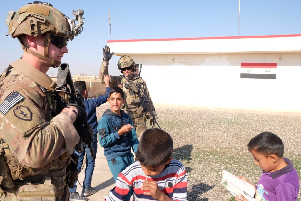 Sergeant First Class Eric Cole high fives a local boy while Sergeant Corbin Mason looks on during a KLE to a village not far outside Q-West. Photo by Kimberly Westenhiser/Coffee or Die.