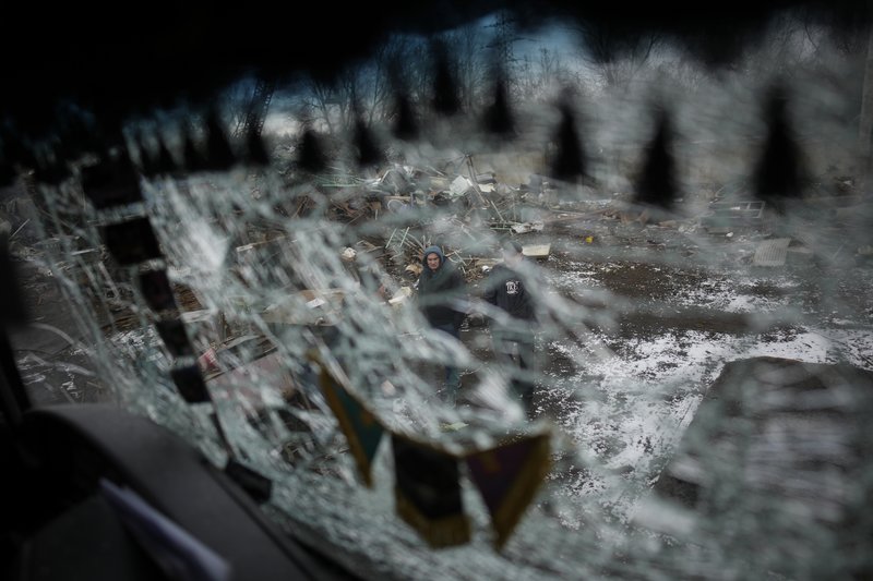 Men are seen through a smashed window of a damaged truck following a rocket attack in Kyiv, Ukraine, Thursday, Jan. 26, 2023. AP Photo by Daniel Cole.