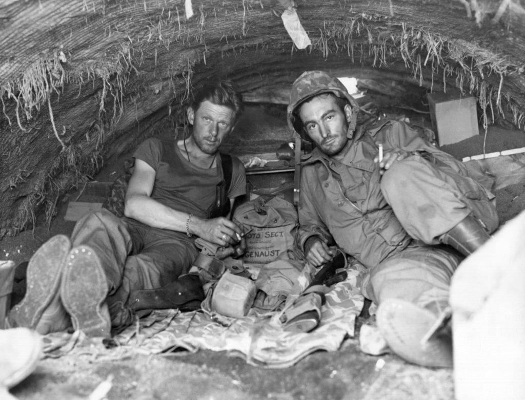 Left, Sergeant W. A. Genaust of St. Paul, Minnesota, and Corporal Atlee S. Tracy of Chicago, movie photographers of the U.S. Marines, take a rest and smoke in their temporary home on Iwo Jima. Photo courtesy of the U.S. Marine Corps.
