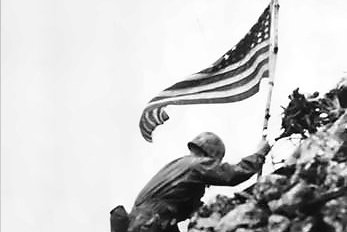 Marine Lt. Col. Richard P. Ross Jr., commander of 3rd Battalion, 1st Marines, braves sniper fire to place the flag over the parapets of Shuri Castle on Okinawa, Japan, May 30, 1945. Photo courtesy of the National Archives.