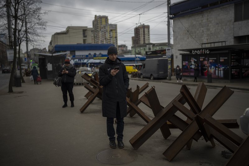 People wait for a bus to arrive in Kyiv, Ukraine, Monday, Jan. 30, 2023. (AP Photo/Daniel Cole)