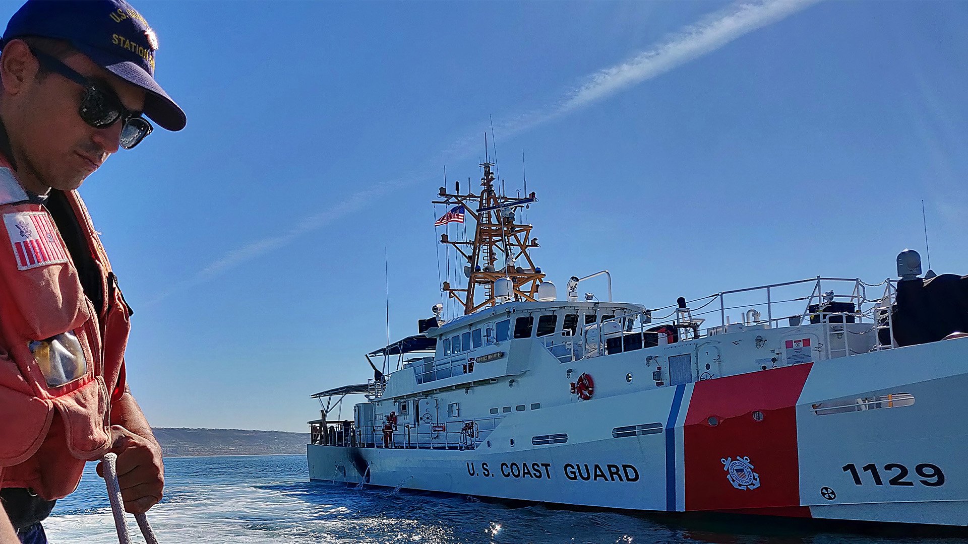 A US Coast Guard fireman ties off a fender on board a Coast Guard Station San Diego 45-foot Response Boat-Medium, with the cutter Forrest Rednour in the background, off the coast of California on Nov. 27, 2018. The crew of the Rednour made the ship's first drug bust during the patrol. US Coast Guard photo.