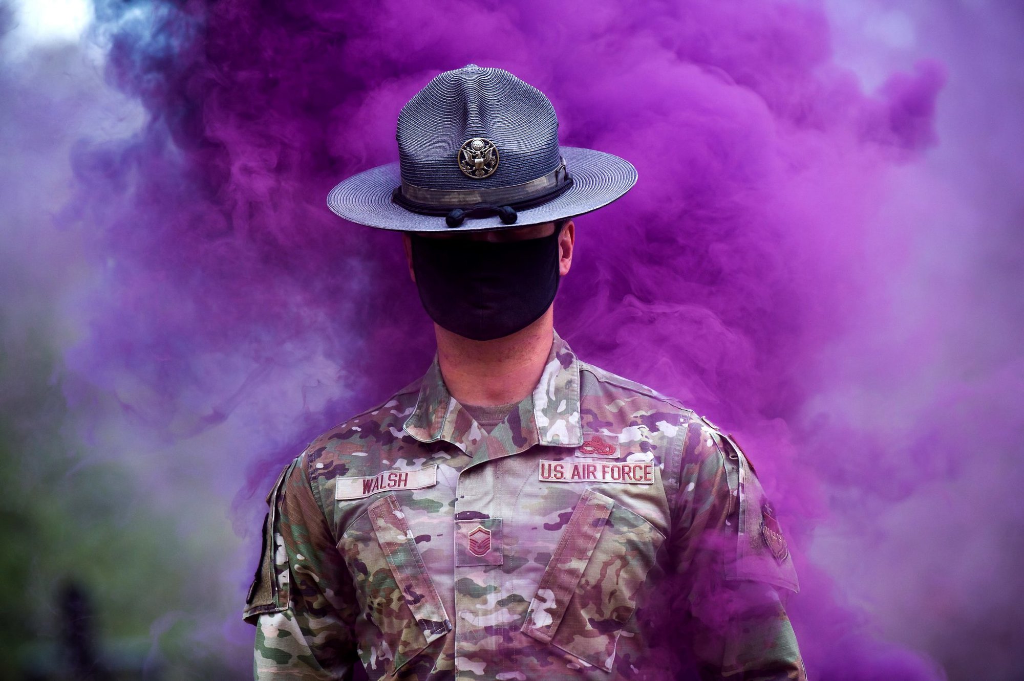 Military Training Instructor Master Sgt. Michael Walsh walks through purple smoke in the Basic Cadet Training assault course at the US Air Force Academy’s Jacks Valley in Colorado Springs, Colorado, July 13, 2021. US Air Force photo by Trevor Cokley, courtesy of DVIDS.